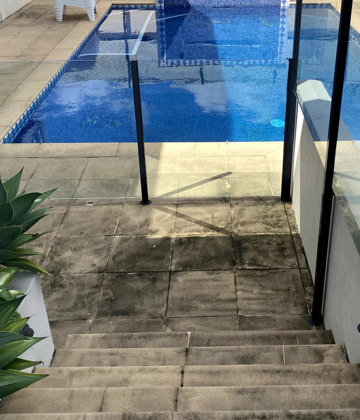 Pool surrounds before cleaning — stained, grimy sandstone pavers